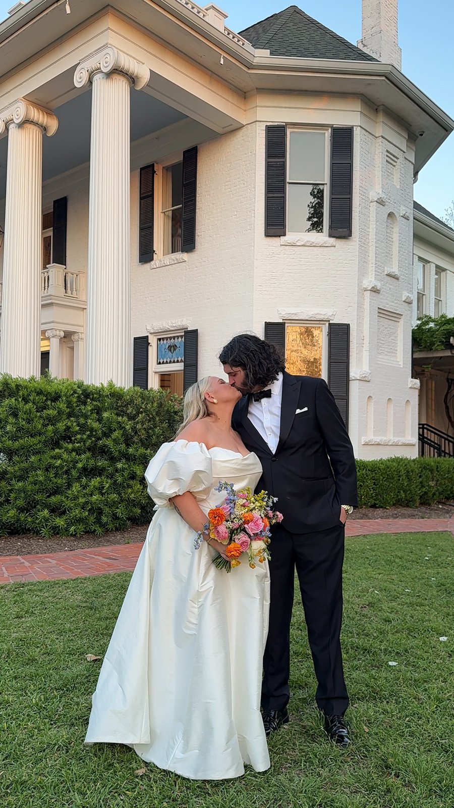 groom kisses bride on the cheek as her veil flows for a wedding at Woodbine Mansion in Round Rock